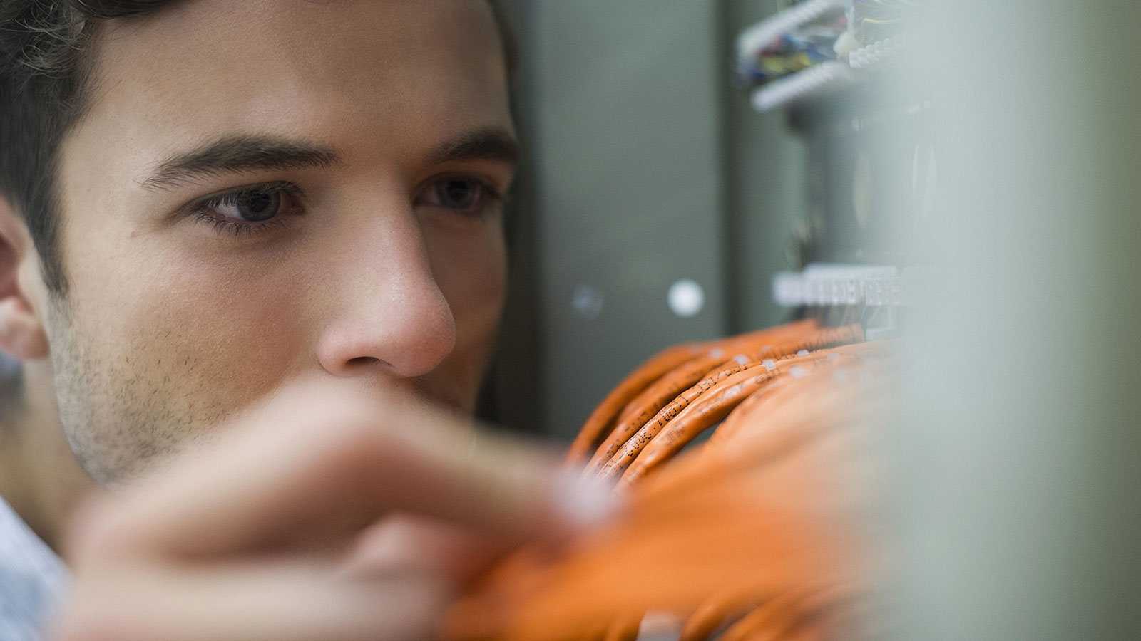 man inspecting ethernet cables in servers