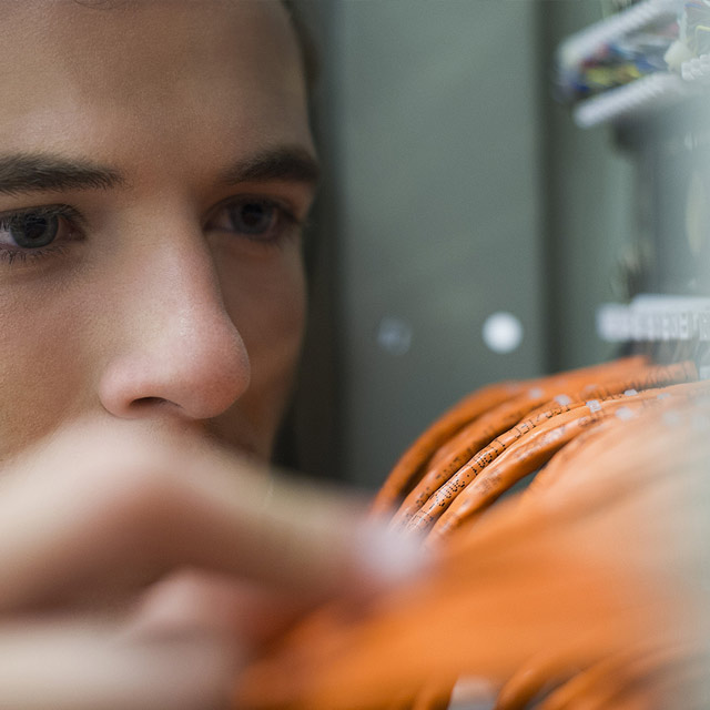 man inspecting ethernet cables in servers