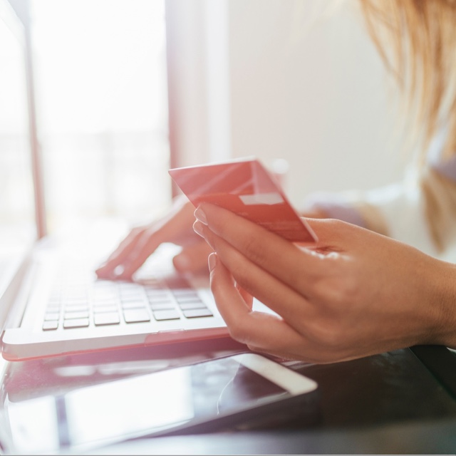 Woman with card and laptop.