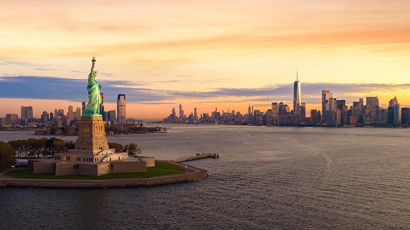 Liberty statue in New York city with manhatttan background and sunset, New York, USA